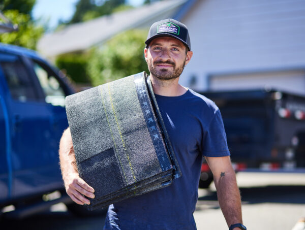 Roofer holding shingles over his shoulder